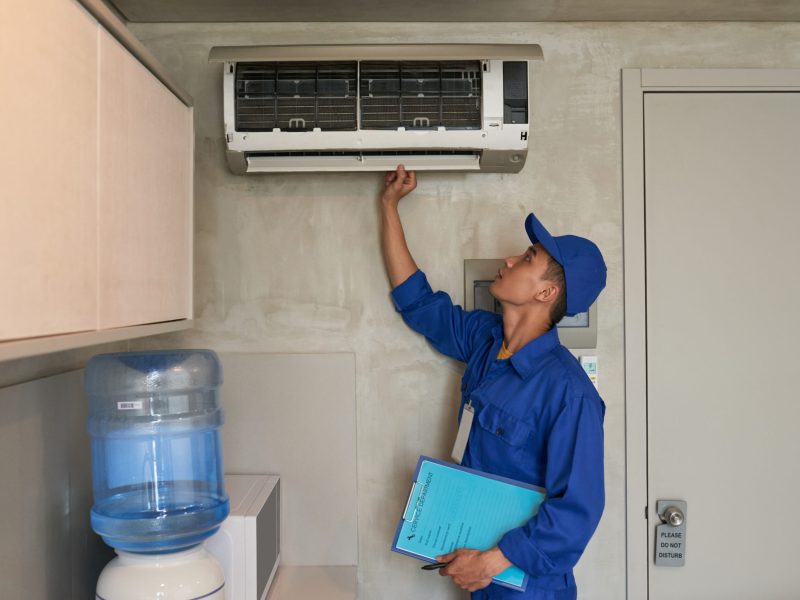 Young Asian technician checking conditioner in kitchen